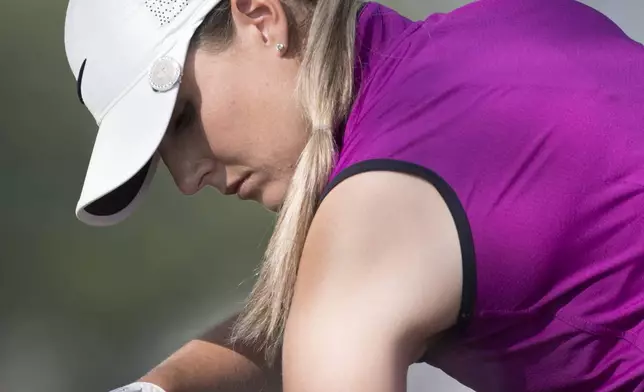 FILE - Megan Osland, of Canada, sprays on sunscreen during the first round of the Women's Canadian Open golf tournament in Regina, Saskatchewan, Thursday, Aug., 23, 2018. Golfers are in the sun as much if not more than players in other sport. It can be as many as eight hours a day. And there is renewed emphasis on protecting their skin. (Jonathan Hayward/The Canadian Press via AP, File)