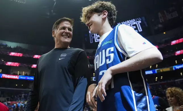 Mark Cuban and his son, Jake Cuban, stand on the sideline before Game 1 of an NBA basketball first-round playoff series against the LA Clippers in Los Angeles, Sunday, April 21, 2024. (AP Photo/Ashley Landis)