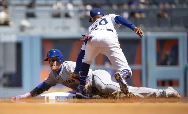 Los Angeles Dodgers shortstop Mookie Betts, right, tags out New York Mets' Harrison Bader who was trying to steal second base during the third inning of a baseball game in Los Angeles, Sunday, April 21, 2024. (AP Photo/Kyusung Gong)