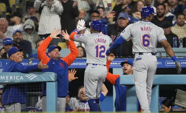 New York Mets' Francisco Lindor (12) returns to the dugout after hitting a home run during the seventh inning of a baseball game against the Los Angeles Dodgers in Los Angeles, Friday, April 19, 2024. Starling Marte (6) also scored. (AP Photo/Ashley Landis)