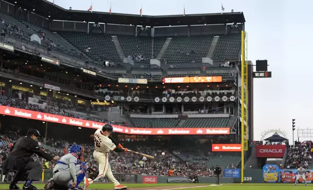 San Francisco Giants' Matt Chapman, third from left, hits a two-run double in front of New York Mets catcher Omar Narváez during the third inning of a baseball game in San Francisco, Monday, April 22, 2024. (AP Photo/Jeff Chiu)