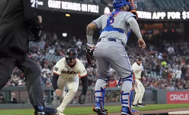 San Francisco Giants' Michael Conforto, bottom, slides home to score past New York Mets catcher Omar Narváez during the second inning of a baseball game in San Francisco, Monday, April 22, 2024. (AP Photo/Jeff Chiu)
