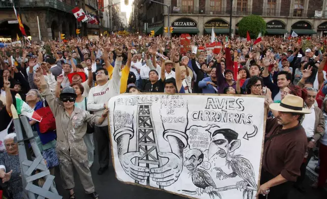 FILE - Supporters of former presidential candidate Manuel Lopez Obrador attend a demonstration organized by Obrador to mark the 70th anniversary of the nationalization of the oil industry in the Zocalo of Mexico City, March 18, 2008. The sign shows Interior Minister Juan Camilo Mourino, right, and President Felipe Calderon, depicted as vultures The writing at left of the sign reads ' the oil belongs to the Mexican people'.( AP Photo/Marco Ugarte, File)