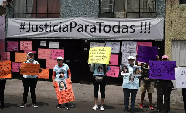 Friends and family holds images of women who have gone missing, during a protest outside an apartment rented by a suspected serial killer, in the Iztacalco neighborhood of Mexico City, Friday, April 26, 2024. Protesters covered the facade of the building with placards after investigators found the bones, cell phones and ID cards of several women at rented rooms there. (AP Photo/Marco Ugarte)