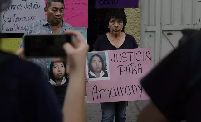Mario Roblero and Cecilia Gonzalez hold images of their missing daughter Amarirany Roblero, during a protest outside an apartment rented by a suspected serial killer, in the Iztacalco neighborhood of Mexico City, Friday, April 26, 2024. Protesters covered the facade of the building with placards after investigators found the bones, cell phones and ID cards of several women at rented rooms there, asking variants of a single question: Why did it take prosecutors 12 years to investigate the disappearance of Amairany Roblero, then 18. (AP Photo/Marco Ugarte)