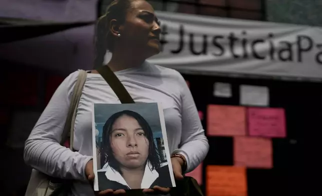 Alejandra Jiménez holds an image of Amarirany Roblero who went missing 12 years ago, during a protest outside an apartment rented by a suspected serial killer, in the Iztacalco neighborhood of Mexico City, Friday, April 26, 2024. Protesters covered the facade of the building with placards after investigators found the bones, cell phones and ID cards of several women at rented rooms there, asking variants of a single question: Why did it take prosecutors 12 years to investigate the disappearance of Amairany Roblero, then 18. (AP Photo/Marco Ugarte)