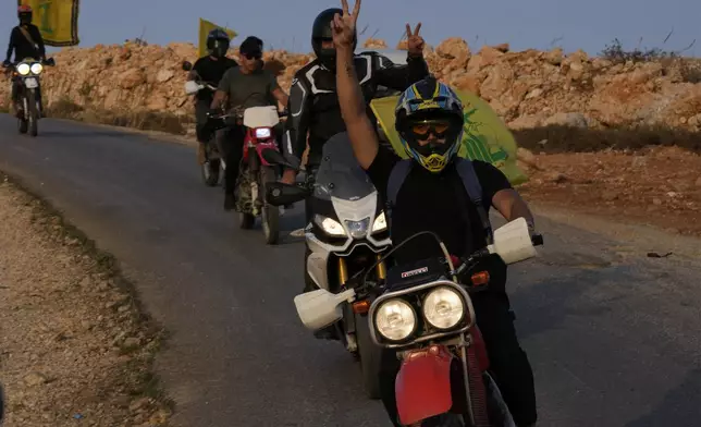 FILE - Hezbollah supporters ride their motorcycles, as they pass on a hill that overlooking to the Israeli town of Metula, at the Lebanese side of the Lebanese-Israeli border in the southern village of Kfar Kila, Lebanon, Sunday, Oct. 8, 2023. A day after Hamas’ attack, the Iran-backed Lebanese Shiite Hezbollah begins firing toward Israel, setting off months of low intensity but deadly cross-border fighting that displaced tens of thousands of people on both sides of the border. (AP Photo/Hussein Malla, File)