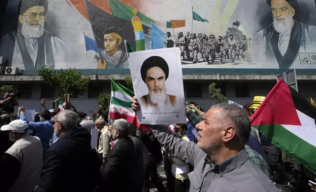 FILE - Iranian worshippers walk past a mural showing the late revolutionary founder Ayatollah Khomeini, right, Supreme Leader Ayatollah Ali Khamenei, left, and Basij paramilitary force, as they hold posters of Ayatollah Khomeini and Iranian and Palestinian flags in an anti-Israeli gathering after Friday prayers in Tehran, Iran, April 19, 2024. This month's unprecedented direct attacks between Iran and Israel are revealing deeper insights into both militaries. Experts say Friday's apparent precision strike by Israel deep into Iran demonstrated Israel's military dominance on almost all fronts. (AP Photo/Vahid Salemi, File)