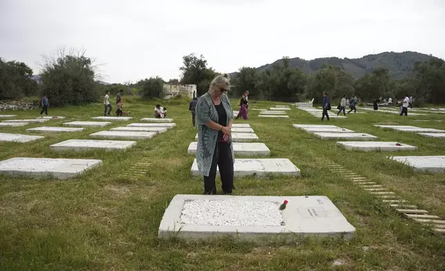 People visit the cemetery at Kato Tritos village on the northeastern Aegean Sea island of Lesbos, Greece, on Wednesday, April 17, 2024. After years of neglect, a primitive burial ground for refugees who died trying to reach Greece's island of Lesbos has been cleaned up and redesigned to provide a dignified resting place for the dead. (AP Photo/Panagiotis Balaskas)