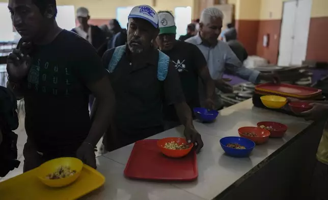 Migrants get a hot meal at the Casa INDI Home and dining room for the poor, a shelter in Monterrey, Mexico, Thursday, April 11, 2024. Migrants are transforming this prosperous industrial city, but aren't part of Mexico's political conversation as the country gears up for its presidential vote on June 2. (AP Photo/Eduardo Verdugo)