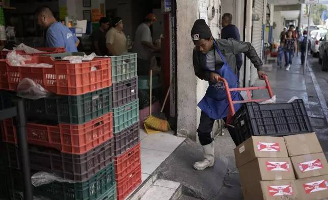 A Haitian migrant worker stacks boxes at a store near a market in Monterrey, Mexico, Thursday, April 11, 2024. Haitian and Central American migrants are transforming this prosperous industrial city, but the new arrivals aren't part of Mexico's political conversation as the country gears up for its presidential vote on June 2. (AP Photo/Eduardo Verdugo)