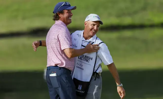 Stephen Ames celebrates with his caddie after making his putt on the 18th green on the 18th hole during the final round of the Mitsubishi Classic senior golf tournament at TPC Sugarloaf, Sunday, April 28, 2024, in Duluth, Ga. (Miguel Martinez/Atlanta Journal-Constitution via AP)