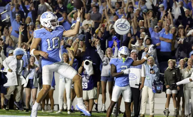 FILE - North Carolina quarterback Drake Maye (10) flips the ball into the air after scoring a rushing touchdown as teammate wide receiver Gavin Blackwell (2) look on during the second overtime of an NCAA college football game against Appalachian State, Saturday, Sept. 9, 2023, in Chapel Hill, N.C. (AP Photo/Reinhold Matay, File)