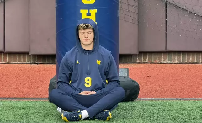 FILE - Michigan quarterback J.J. McCarthy sits on the field with his back against a padded goalpost on Nov. 4, 2023 in Ann Arbor, Mich. McCarthy meditates roughly two hours before games. McCarthy is a possible first round pick in the NFL Draft.(AP Photo/Larry Lage, File)