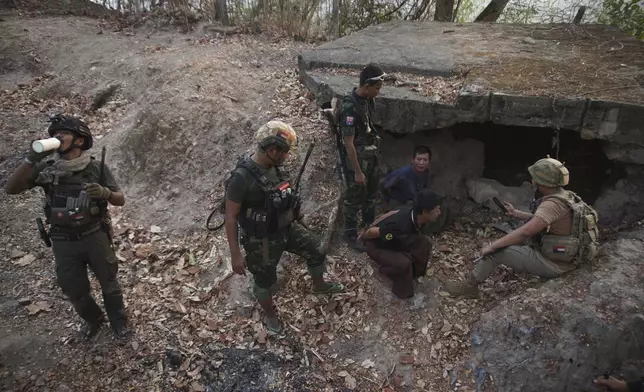 Members of the Karen National Liberation Army and People’s Defense Force examine two arrested soldiers after they captured an army outpost, in the southern part of Myawaddy township in Kayin state, Myanmar, March 11, 2024. (AP Photo/METRO)
