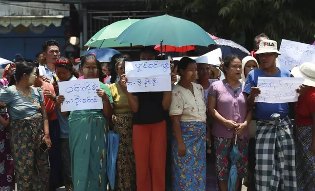 Family members and colleagues wait for prisoners to be released from Insein Prison Wednesday, April 17, 2024, in Yangon, Myanmar. On Wednesday Myanmar's military government granted amnesty for over 3,000 prisoners to mark this week’s traditional New Year holiday. The signs show their family name. (AP Photo/Thein Zaw)