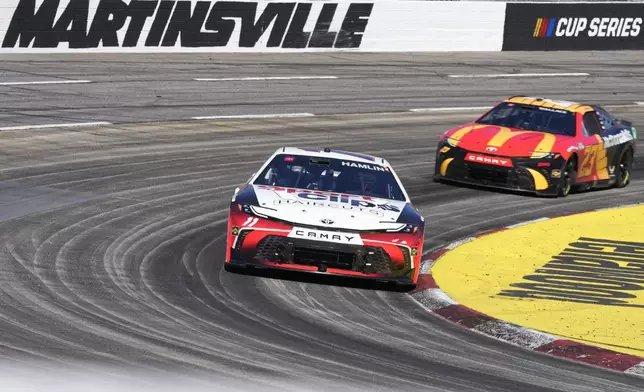 Denny Hamlin (11) leads Bubba Wallace (23) out of Turn 4 during a NASCAR Cup Series auto race at Martinsville Speedway in Martinsville, Va., Sunday, April 7, 2024. (AP Photo/Chuck Burton)