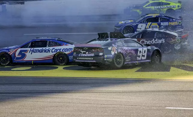 NASCAR Cup Series driver's Kyle Larson (5) and Daniel Suarez (99) collide during a collision on the final lap of a NASCAR Cup Series auto race at Talladega Superspeedway, Sunday, April 21, 2024, in Talladega. Ala. (AP Photo/Mike Stewart)