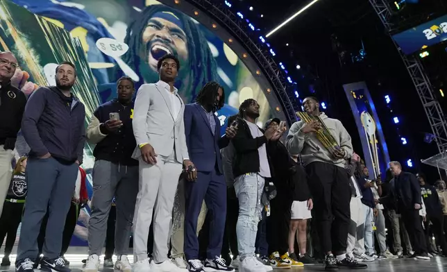 Michigan football players stand on stage during the second round of the NFL football draft, Friday, April 26, 2024, in Detroit. (AP Photo/Jeff Roberson)