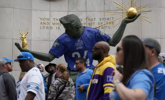 Fans walk by a statue during the third day of the NFL football draft, Saturday, April 27, 2024, in Detroit. (AP Photo/Jeff Roberson)