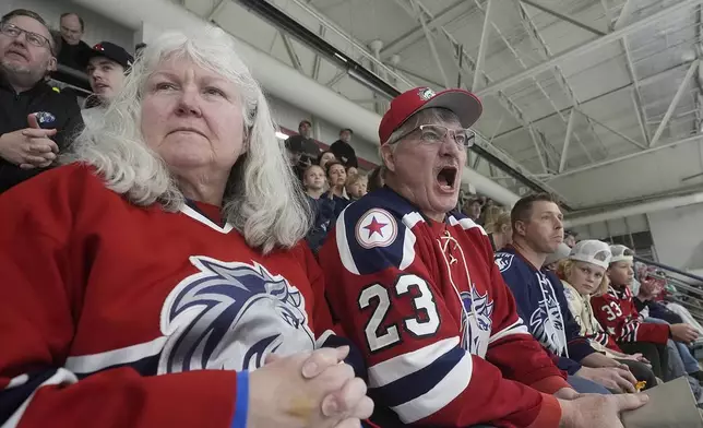 Wayne, center, and Holly Haacke, front left, support their team, the Ogden Mustangs, as they play the Utah Outliers during the Mountain Division Championship game Wednesday, April 17, 2024, in West Valley City, Utah. It may look like an NHL team has just fallen into Salt Lake City's lap. But local organizers say the Arizona Coyotes' relocation to Utah is the product of a yearslong effort to beckon professional hockey and other elite sports to the capital city. (AP Photo/Rick Bowmer)