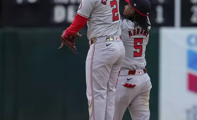 Washington Nationals second baseman Luis García Jr. (2) and shortstop CJ Abrams celebrate the team's victory over the Oakland Athletics in a baseball game Saturday, April 13, 2024, in Oakland, Calif. (AP Photo/Godofredo A. Vásquez)