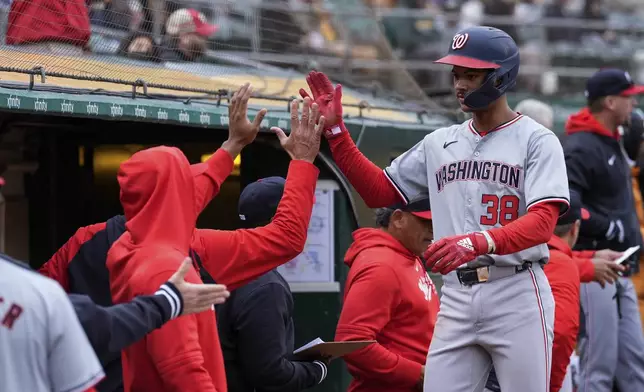 Washington Nationals' Trey Lipscomb (38) celebrates with teammates at the dugout after scoring against the Oakland Athletics on Jacob Young's double during the ninth inning of a baseball game Saturday, April 13, 2024, in Oakland, Calif. (AP Photo/Godofredo A. Vásquez)