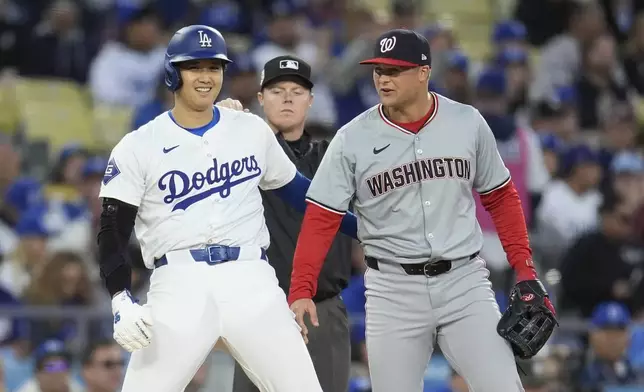 Los Angeles Dodgers' Shohei Ohtani, left, jokes with Washington Nationals third baseman Nick Senzel during the first inning of a baseball game Monday, April 15, 2024, in Los Angeles. (AP Photo/Marcio Jose Sanchez)
