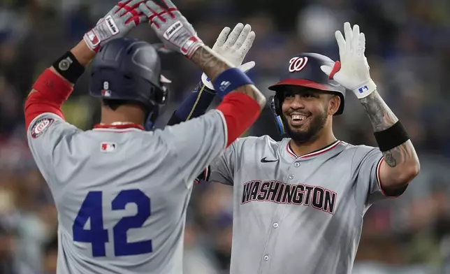 Washington Nationals' Luis Garcia Jr., right, celebrates with teammate with Eddie Rosario after hitting a three-run home run during the fifth inning of a baseball game against the Los Angeles Dodgers, Monday, April 15, 2024, in Los Angeles. (AP Photo/Marcio Jose Sanchez)