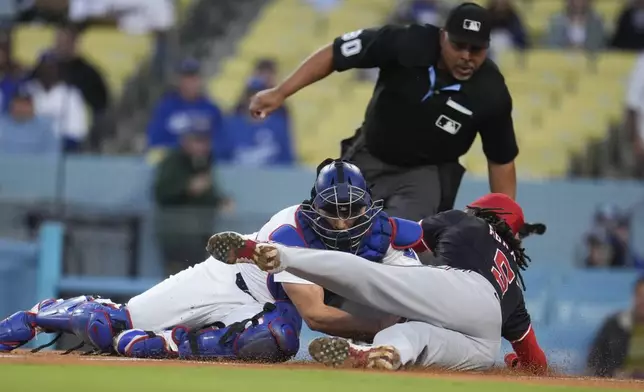 Los Angeles Dodgers catcher Austin Barnes, left, tags out Washington Nationals' CJ Abrams at home plate after a double by Jesse Winker during the first inning of a baseball game Tuesday, April 16, 2024, in Los Angeles. (AP Photo/Marcio Jose Sanchez)