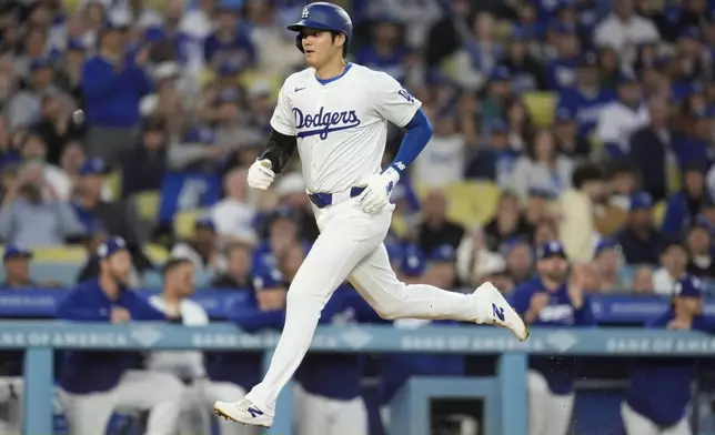Los Angeles Dodgers' Shohei Ohtani scores on a sacrifice fly by teammate Will Smith during the first inning of a baseball game against the Washington Nationals, Monday, April 15, 2024, in Los Angeles. (AP Photo/Marcio Jose Sanchez)