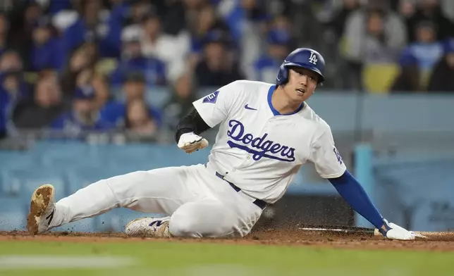Los Angeles Dodgers' Shohei Ohtani scores on a ground ball by Freddie Freeman during the sixth inning of a baseball game against the Washington Nationals, Monday, April 15, 2024, in Los Angeles. (AP Photo/Marcio Jose Sanchez)