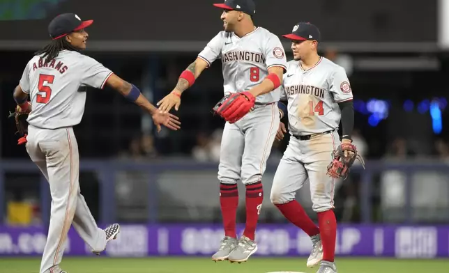 Washington Nationals shortstop CJ Abrams (5), center fielder Eddie Rosario (8) and second baseman Ildemaro Vargas (14) celebrate after their victory over the Miami Marlins in a baseball game, Monday, April 29, 2024, in Miami. (AP Photo/Lynne Sladky)