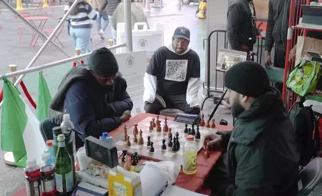 In this screen grab taken from video, Tunde Onakoya, 29- years old, a Nigerian chess champion and child education advocate, left, play a chess game in Times Square, New York, Thursday, April, 18, 2024.A Nigerian chess player and child education advocate is attempting to play chess nonstop for 58 hours in New York City's Times Square to break the global record for the longest chess marathon and raise $1m for the education of children across Africa. (AP Video/John Minchillo)