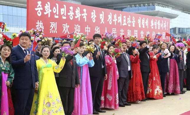 Pyongyang citizens welcome a Chinese delegation headed by Zhao Leji, chairman of the National People’s Congress and considered the No. 3 official in the ruling Communist Party, as they arrive at the Pyongyang International Airport in Pyongyang, North Korea, Thursday, April 11, 2024. The banner in the background says, "Warmly welcome the party and government delegation of the People's Republic of China!" (AP Photo/Cha Song Ho)
