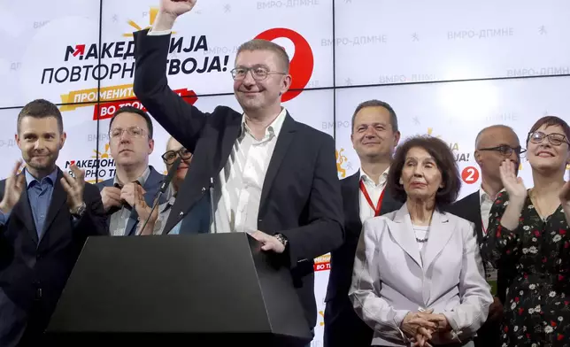 Hristijan Mickoski, center left, the leader of the opposition conservative VMRO-DPMNE party, raises his fist next to their presidential candidate Gordana Siljanovska Davkova, center right, during a news conference, after winning in the first round of the presidential election, in Skopje, North Macedonia, late Wednesday, April 24, 2024. Siljanovska Davkova has a big lead ahead of Stevo Pendarovski, the candidate of the Social Democrats and they both will face each other in the second round of the presidential election that will coincide with the general election on May 8. (AP Photo/Boris Grdanoski)