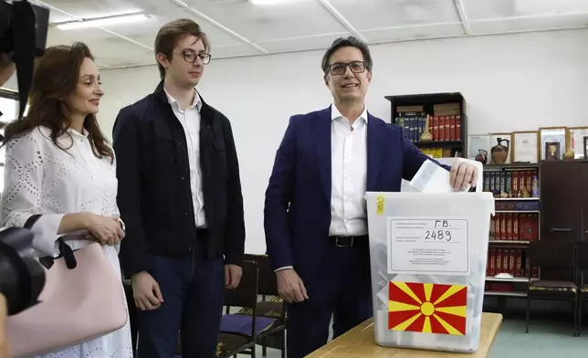 Stevo Pendarovski, incumbent President and a presidential candidate backed by the ruling social democrats (SDSM), right, casts his ballot in presence of his wife Elizabeta Gjorgievska, left and their son Ognen, center, at a polling station in Skopje, North Macedonia, on Wednesday, April 24, 2024. People are lining up at pools to cast their votes in a peaceful atmosphere, hoping that the next president will be able to bring the country into the European Union. (AP Photo/Boris Grdanoski)