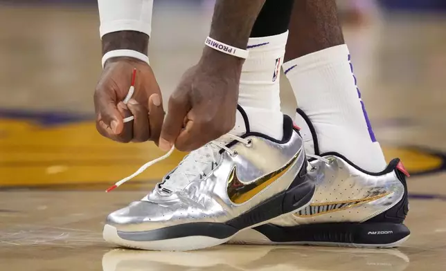 Los Angeles Lakers forward LeBron James ties his shoes during the first half in Game 4 of an NBA basketball first-round playoff series against the Denver Nuggets Saturday, April 27, 2024, in Los Angeles. (AP Photo/Mark J. Terrill)