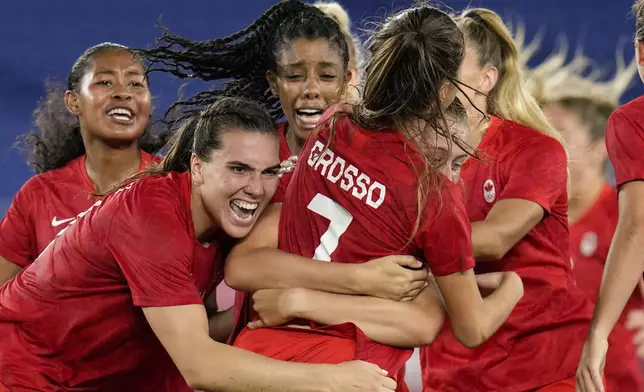 FILE - Teammates embrace Canada's Julia Grosso after she scored the winning goal against Sweden in the women's soccer match for the gold medal at the 2020 Summer Olympics, Friday, Aug. 6, 2021, in Yokohama, Japan. (AP Photo/Fernando Vergara, File)