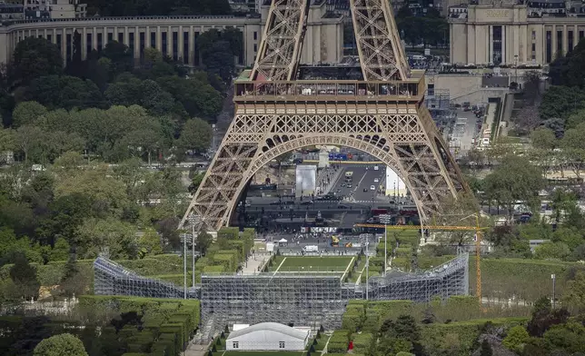 Stands are under construction on the Champ-de-Mars, foreground, with the Eiffel Tower in background, Monday, April 15, 2024 in Paris. The Champ-de-Mars will host the Beach Volleyball and Blind Football at the Paris 2024 Olympic and Paralympic Games. (AP Photo/Aurelien Morissard)