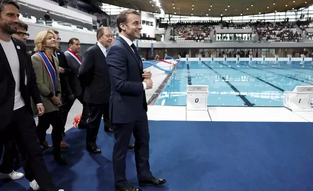 French President Emmanuel Macron, surrounded by Tony Estanguet, president of the Paris 2024 Olympics Organising Committee, left, Ile-de-France's Regional Council President Valerie Pecresse, third left, and Grand Paris' Metropole President Patrick Ollier visit the Olympic Aquatics Center (CAO), a multifunctional venue for the 2024 Paris Olympic in Saint-Denis, near Paris, Thursday, April 4, 2024. The aquatic center will host the artistic swimming, water polo and diving events during the Paris 2024 Olympic Games. (Gonzalo Fuentes/Pool via AP)
