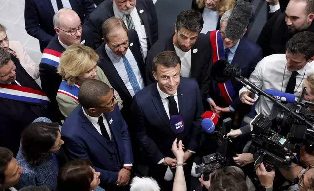 French President Emmanuel Macron, center, speaks to journalists during the inauguration of the Olympic Aquatics Center (CAO) in Saint-Denis, near Paris, Thursday, April 4, 2024. The aquatic center will host the artistic swimming, water polo and diving events during the Paris 2024 Olympic Games. (Gonzalo Fuentes/Pool via AP)