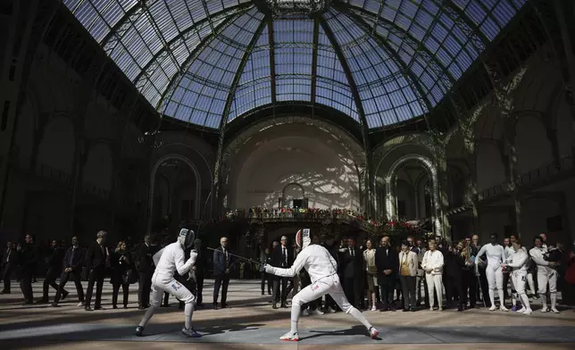 French President Emmanuel Macron attends a demonstration by the French fencing team as he visits the Grand Palais ahead of the Paris 2024 Olympic Games in Paris, Monday, April15, 2024. The Grand Palais will host the Fencing and Taekwondo competitions during the Paris 2024 Olympic Games. (Yoan Valat, Pool via AP)