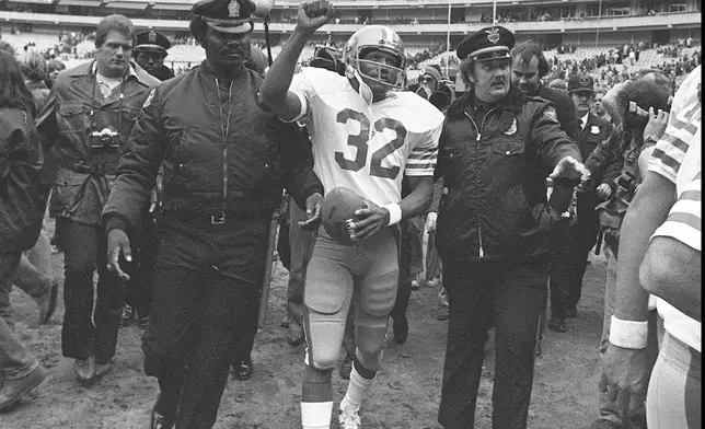 FILE - San Francisco 49ers running back O.J. Simpson is escorted from the field by police after the final NFL football game of his career, Dec. 16, 1979, against in the Atlanta Falcons at Atlanta Fulton County Stadium in Atlanta, Ga. Simpson, the decorated football superstar and Hollywood actor who was acquitted of charges he killed his former wife and her friend but later found liable in a separate civil trial, has died. He was 76. (AP Photo, File)