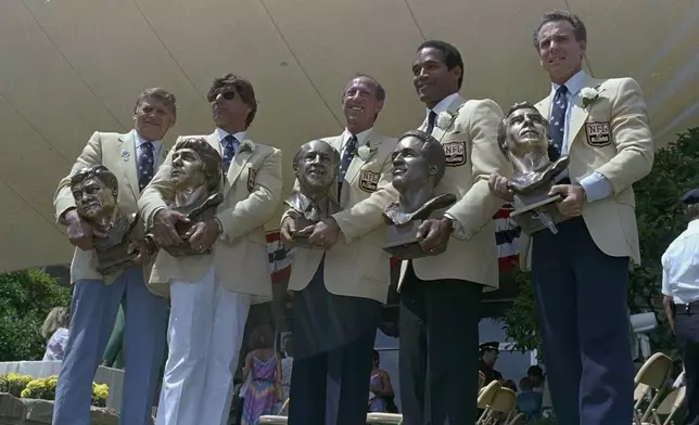 FILE - O.J. Simpson, second from right is joined by, from left, Frank Gatski, Joe Namath, Pete Rozelle, and Roger Staubach, right, during enshrinement ceremonies at the Pro Football Hall of Fame in Canton, Ohio, Aug. 3, 1985. O.J. Simpson, the decorated football superstar and Hollywood actor who was acquitted of charges he killed his former wife and her friend but later found liable in a separate civil trial, has died. He was 76. (AP Photo/Ernie Mastroianni, File)