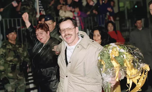 FILE - AP chief Middle East correspondent Terry Anderson, center, accompanied by his sister Peggy Say, left, and Madeleine Bassil, right, smiles broadly upon his arrival at the Wiesbaden Air Force hospital in Germany, Dec. 5, 1991, a day after being released by his abductors in Beirut, where he was held captive for almost seven years. Anderson died Sunday, April 21, 2024, at age 76. (AP Photo/Thomas Kienzle, File)
