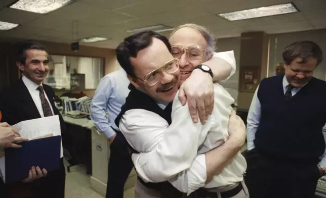 FILE - Former hostage and Associated Press Middle East chief correspondent Terry Anderson, center left, hugs colleague Jim Abrams during a visit to the Washington bureaus of The Associated Press in Washington, Dec. 12, 1991. Anderson, the globe-trotting Associated Press correspondent who became one of America’s longest-held hostages after he was snatched from a street in war-torn Lebanon in 1985 and held for nearly seven years, died Sunday, April 21, 2024, at age 76. (AP Photo/Greg Gibson, File)