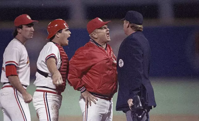 FILE - St. Louis Cardinals manager Whitey Herzog lets umpire John Shulock, right, know how he feels about Shulock's call on the tag attempt on Kansas City Royals Jim Sundberg by Cardinals catcher Tom Nieto, second from left, in the second inning of Game 5 of the World Series in St. Louis, Mo., Oct. 24, 1985. Shulock had ruled Sundberg safe on the play. The Cardinal player at far left is unidentified.Herzog, the gruff and ingenious Hall of Fame manager who guided the St. Louis Cardinals to three pennants and a World Series title in the 1980s and perfected an intricate, nail-biting strategy known as "Whiteyball," has died. He was 92. Cardinals spokesman Brian Bartow said Tuesday, April 16, 2024, the team had been informed of his death by Herzog's family. (AP Photo/Peter Southwick, File)