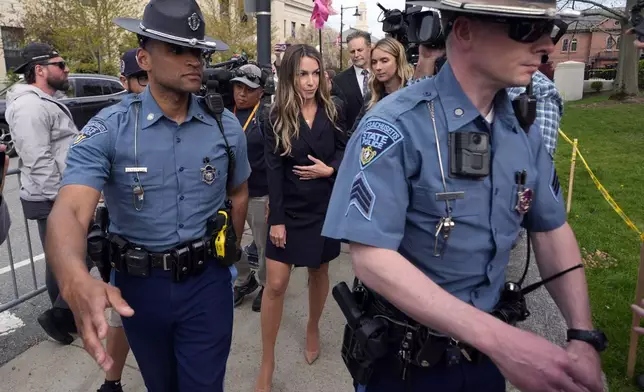 Karen Read, center, is flanked by Massachusetts State Police while leaving Norfolk Superior Court after the opening day of her trial, Monday, April 29, 2024, in Dedham, Mass. Read is charged with killing her Boston police officer boyfriend by intentionally driving her SUV into him. (AP Photo/Charles Krupa)