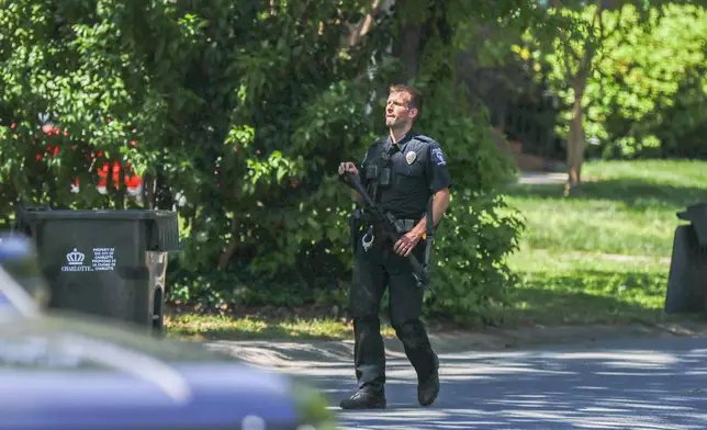 A Charlotte Mecklenburg police officer walks in the neighborhood where several officers on a task force trying to serve a warrant were shot in Charlotte, N.C., Monday, April 29, 2024. (AP Photo/Nell Redmond)
